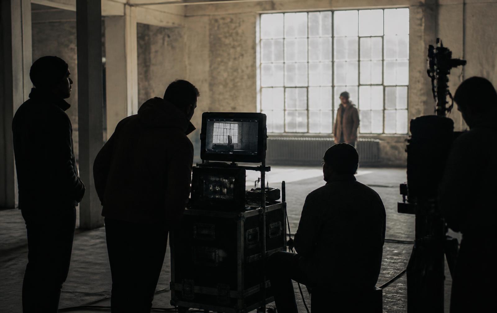 Production crew watching a monitor on set inside a warehouse location